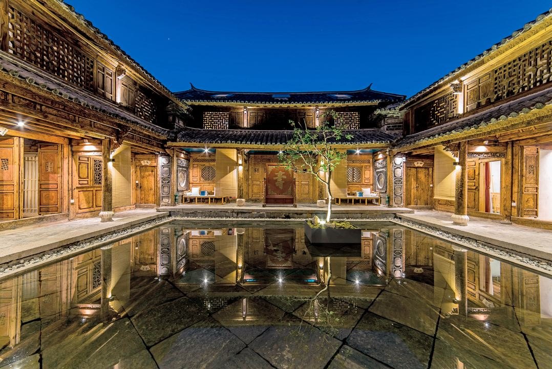 夜里亮着灯的甲科第院子，天井水面映着木雕楼阁 / The courtyard of Jiakedi lit at night, its pool reflecting the carved wooden galleries