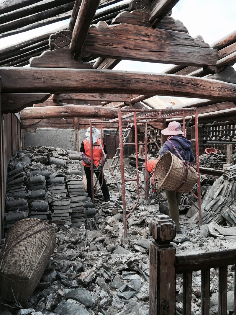 拆下来的瓦片堆在院里，工人用笸箩往外挑 / Fallen tiles piled in the yard while workers carry them out in baskets