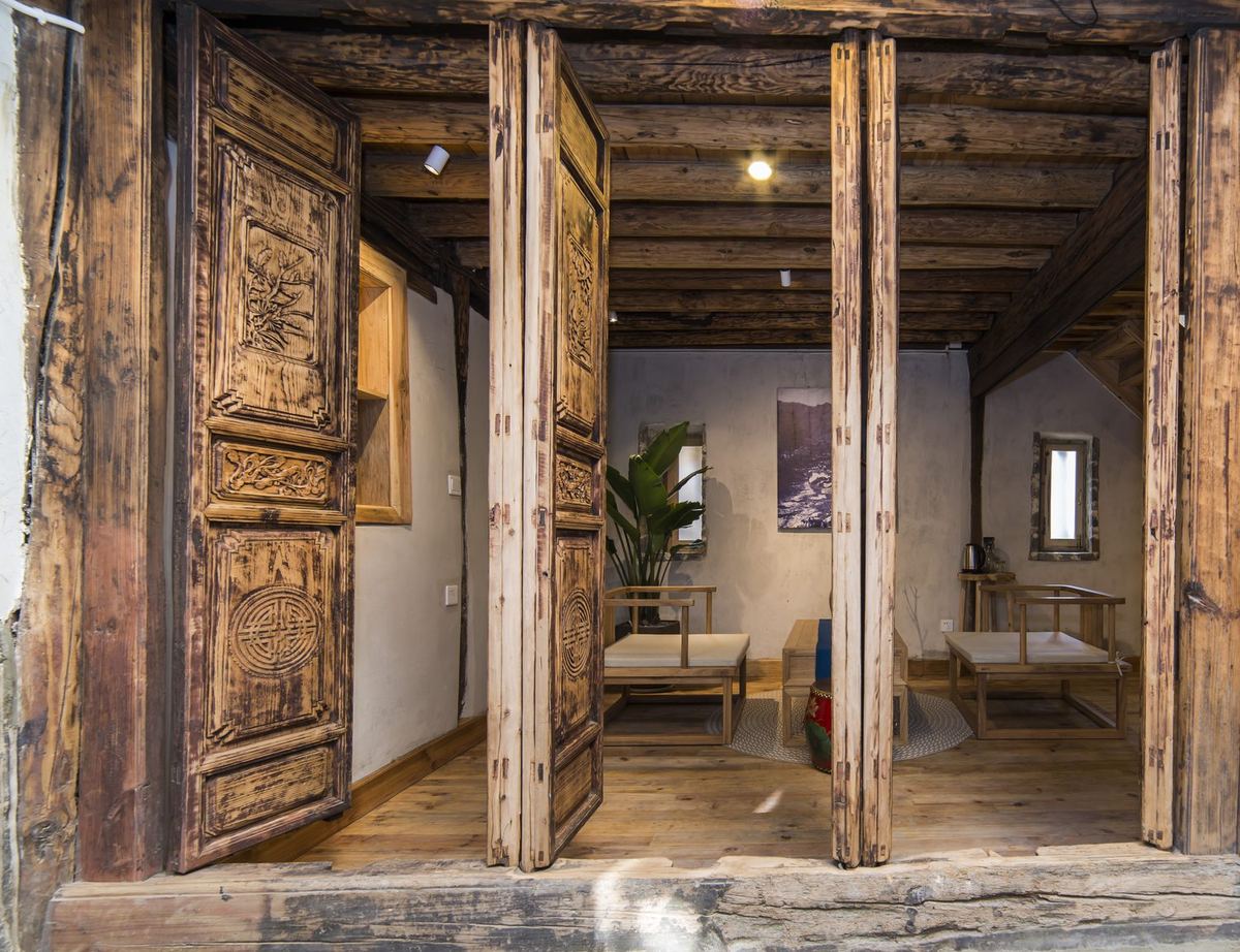 房间里敞开的雕花木门与木梁 / Carved wooden doors and beams inside a room